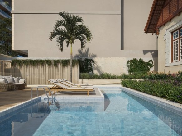 Piscina com espreguiçadeiras e palmeira, ao lado da casa histórica
