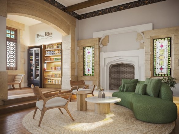 Lounge com sofá verde e lareira, ao lado das prateleiras do minimercado, com vitrais nas janelas