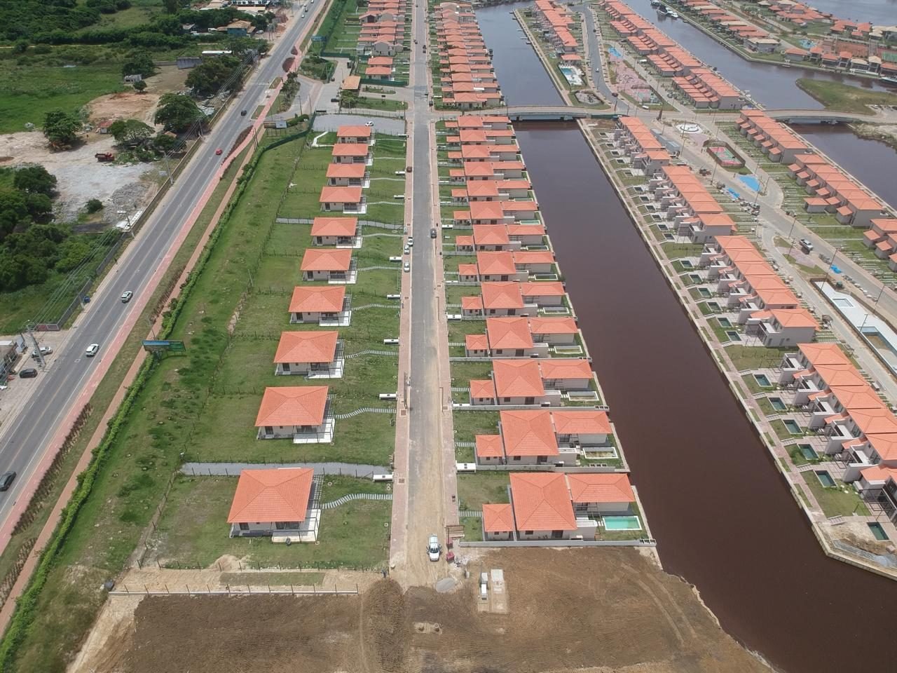 Vista aérea de um canal do Toriba entre duas fileiras de casas, com a estrada à esquerda (foto real)