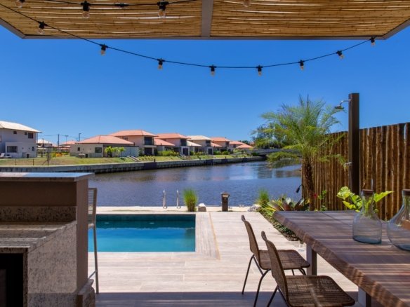 Varanda da casa 10 do Condomínio B do Toriba Norte, decorada, com mesa, piscina e o canal ao fundo (foto real)