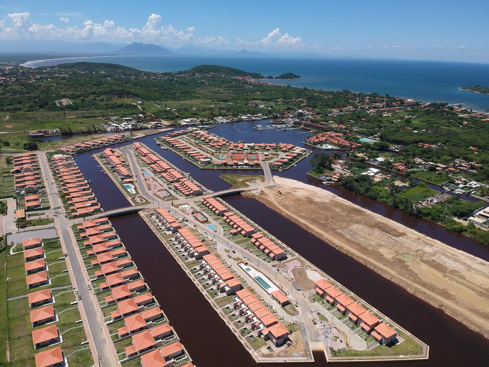 Vista do alto do Toriba em direção ao mar (foto real) Vista aérea do Toriba, com os canais e as casas em primeiro plano e o mar e ilhas ao fundo (foto real)