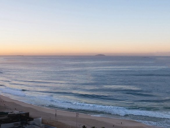 Panorâmica ao nascer do sol: a torre à esquerda, a praia, a pedra do Arpoador e as Ilhas Cagarras no horizonte.