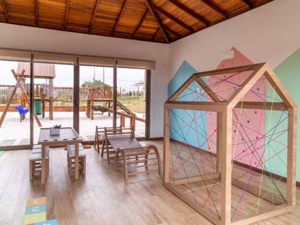 Brinquedoteca com uma casinha de madeira e cordas coloridas, e portas de vidro para o espaço criança, no Alto Ybirá (foto real)