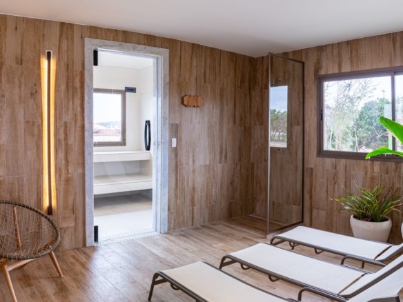 Espaço de descanso da sauna, com espreguiçadeiras, poltrona e paredes de madeira, no Alto Ybirá (foto real)